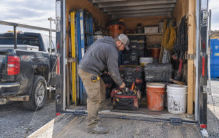 Contractor selecting tools and materials from a work trailer for the day’s job.
